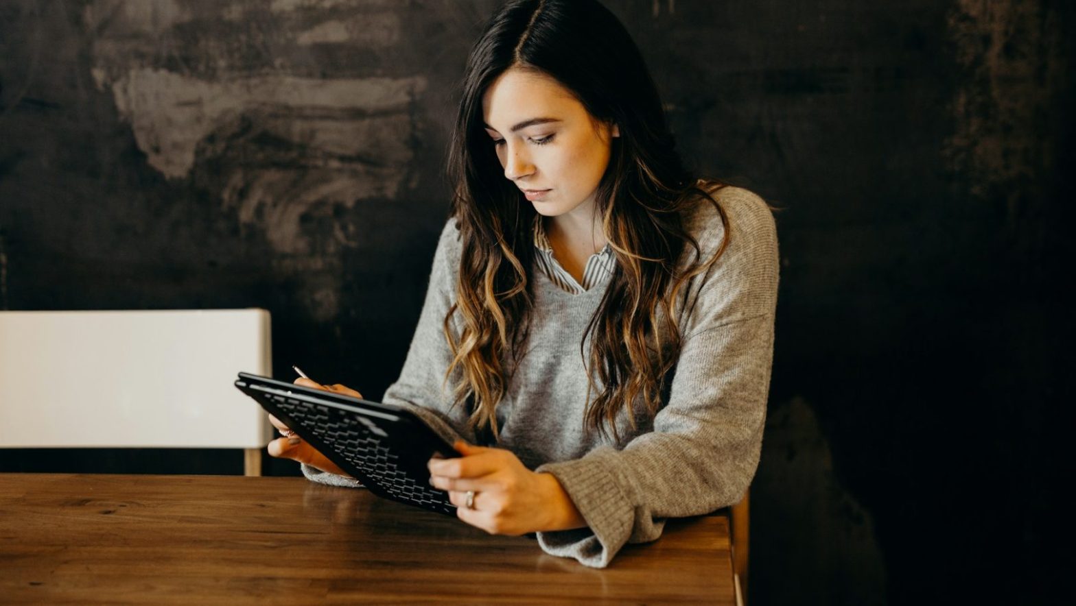 woman wearing white dress shirt using holding black leather case on brown wooden table