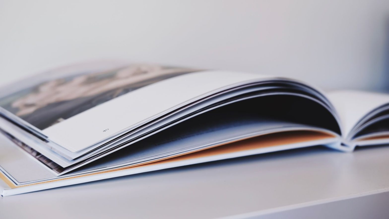 Close-up of an open magazine lying on a white surface, showcasing glossy pages.