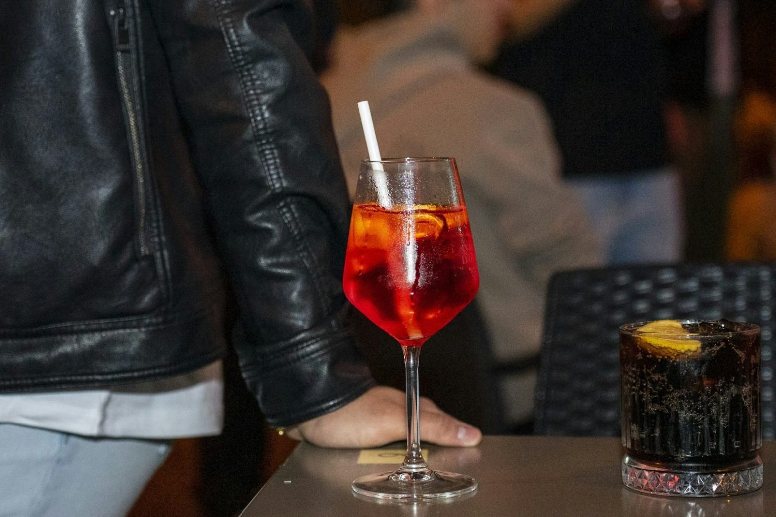A close up of a person sitting at a table with a drink
